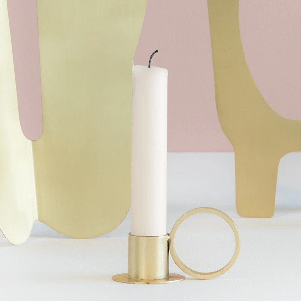 Circle brass-finish iron candleholder, styled with a candle against a pastel pink background.