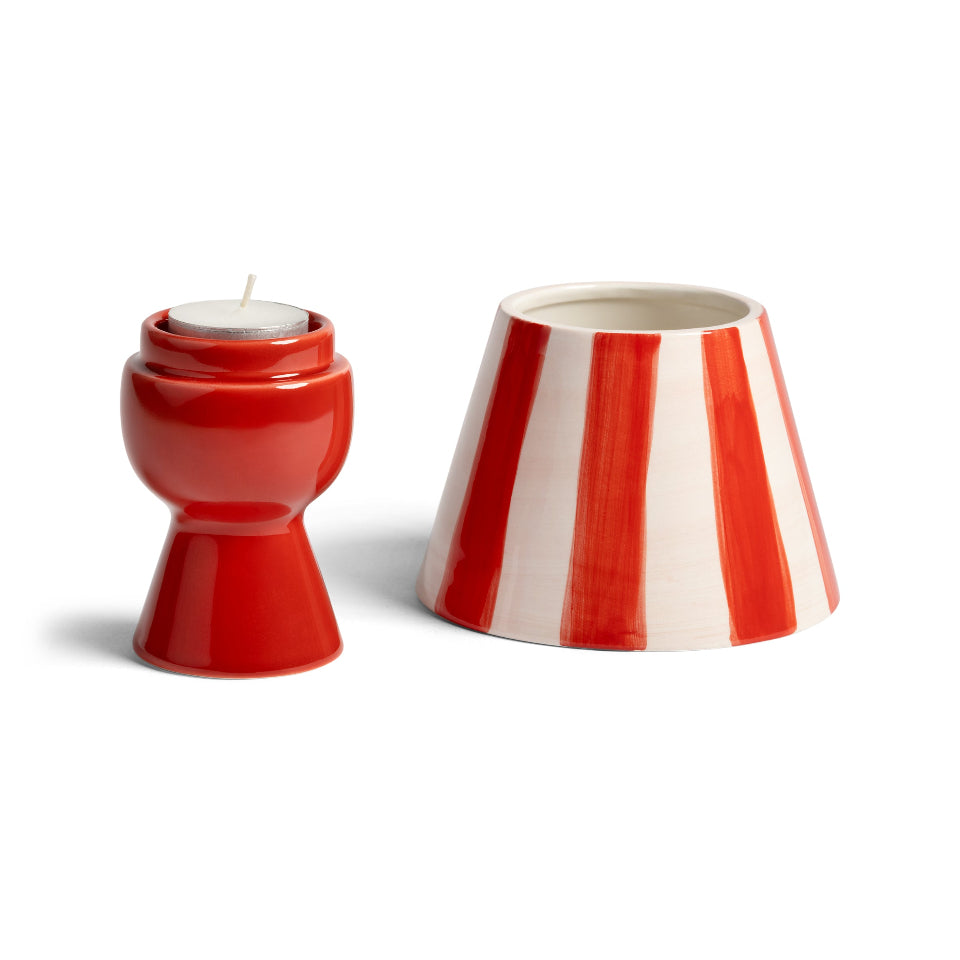 Red and white striped candle holder with a lit candle on a white background