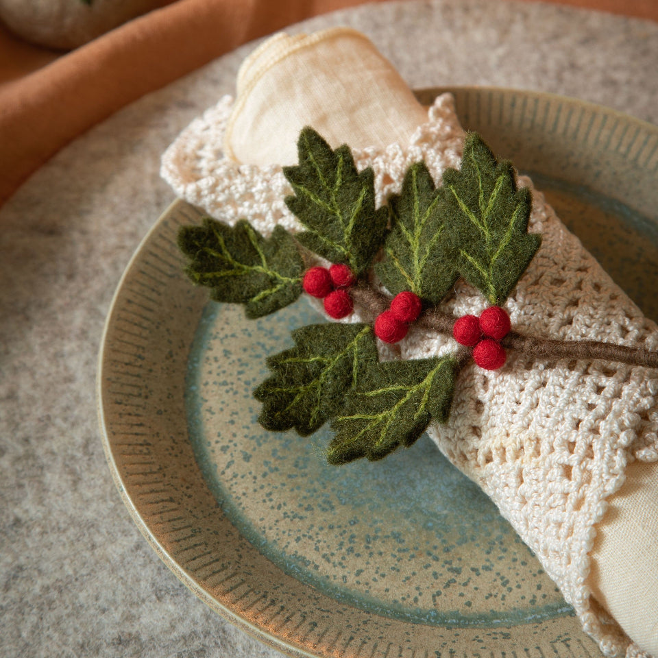 felt holly branch on top of a folded napkin on a green plate