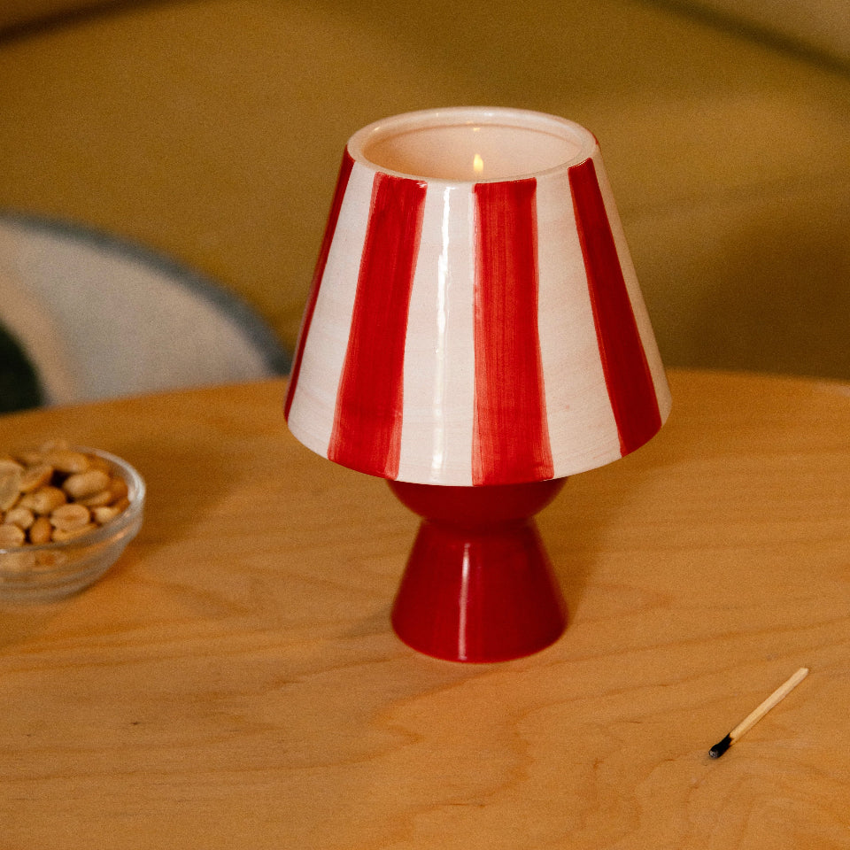 Red and white striped candle holder on a wooden table with a blurred background