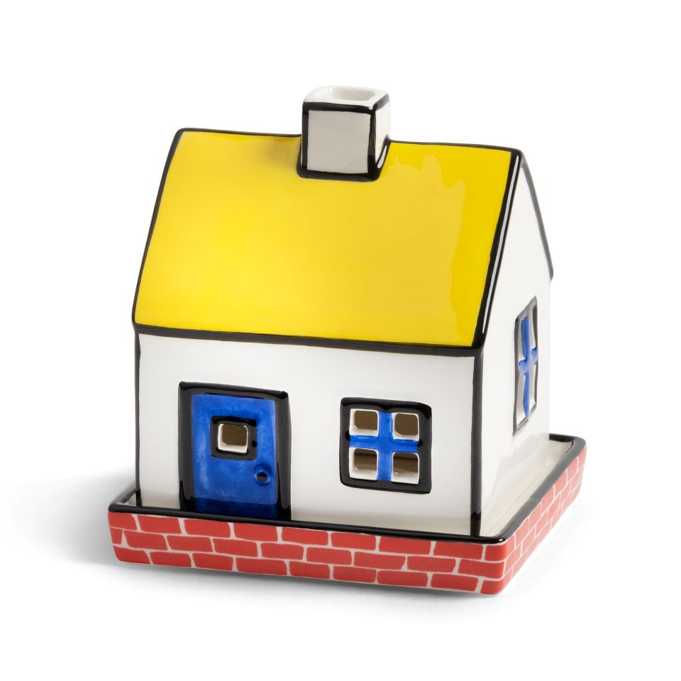 House-shaped candle holder with a yellow roof, white walls, and red base on a white background
