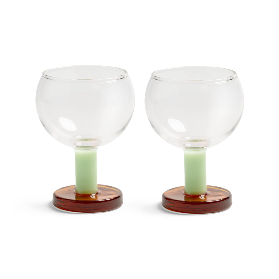 Two clear glass goblets  with brown bases on a white background