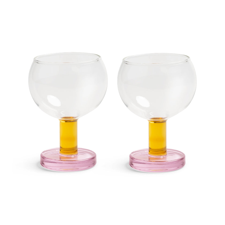 Two clear glass goblets with pink bases and yellow stems on a white background