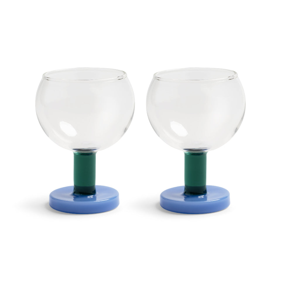 Two clear glass goblets with green stems and blue bases on a white background