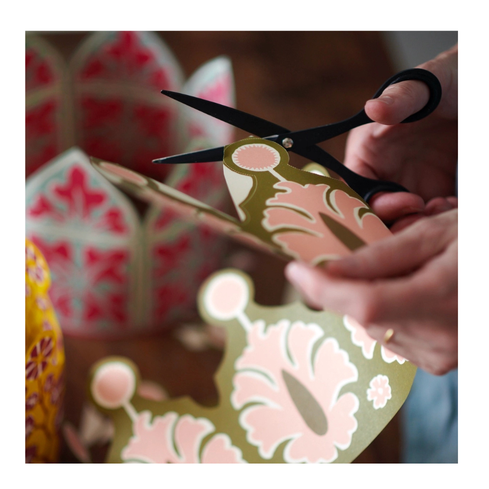 Person cutting a floral paper shape with scissors