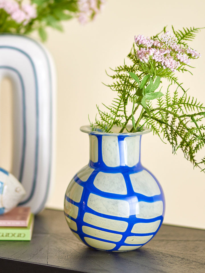Blue and white patterned vase with greenery on a wooden surface