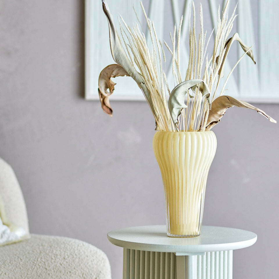 Decorative vase with dried plants on a table against a neutral wall