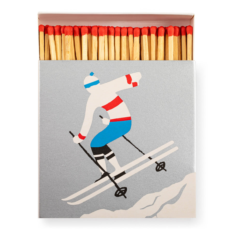 Matchbox with a skier illustration on a gray background