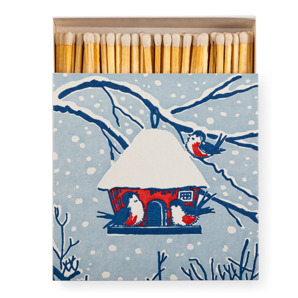 Matches in a box with a winter scene design featuring a house and birds.