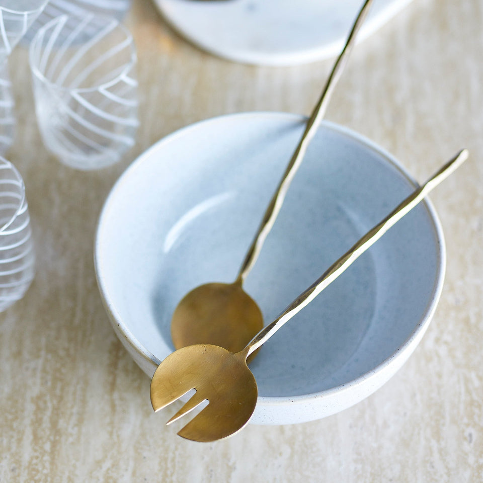 Brass Salad Servers on a white plate with a blurred background