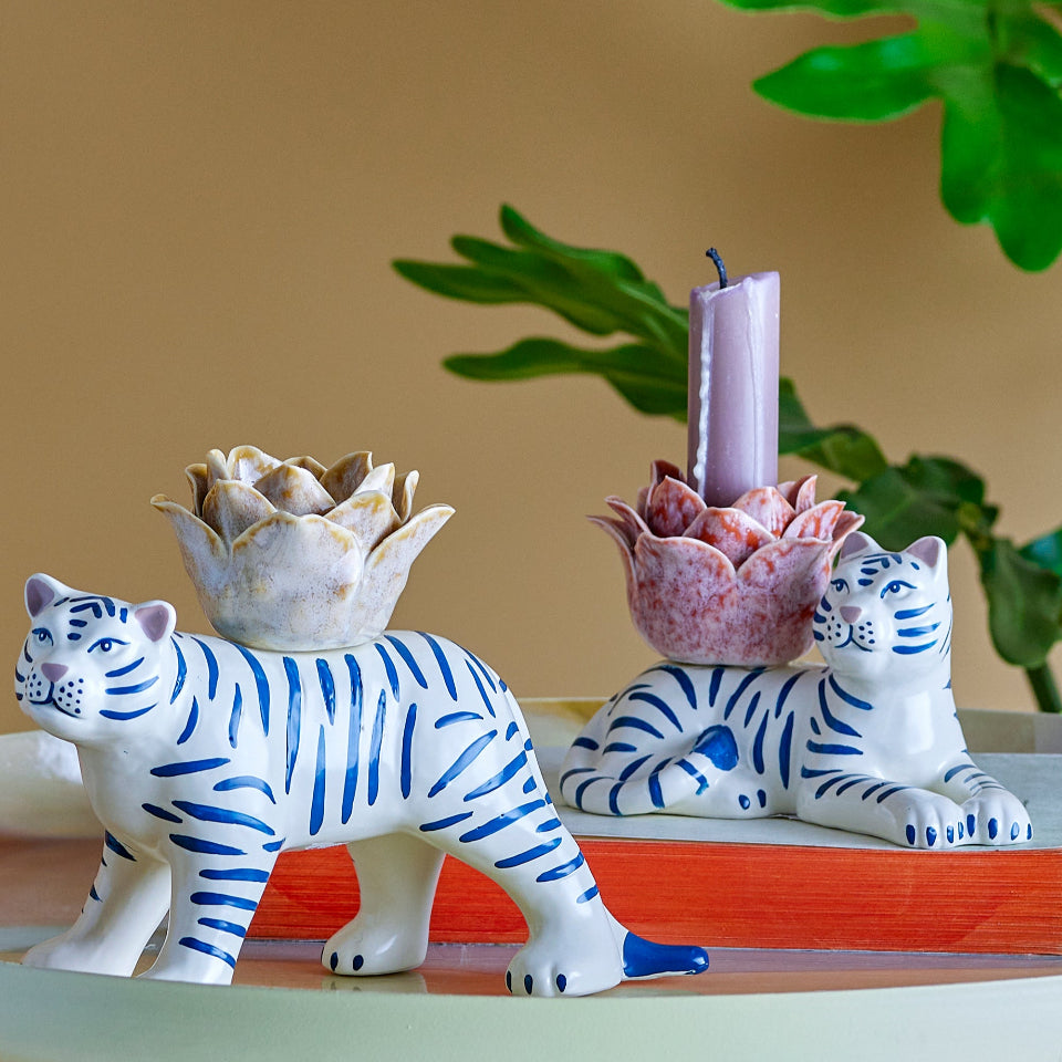 Decorative items including a blue and white tiger figurine, pink candle holder with succulent, and white tiger figurine on a wooden stand.