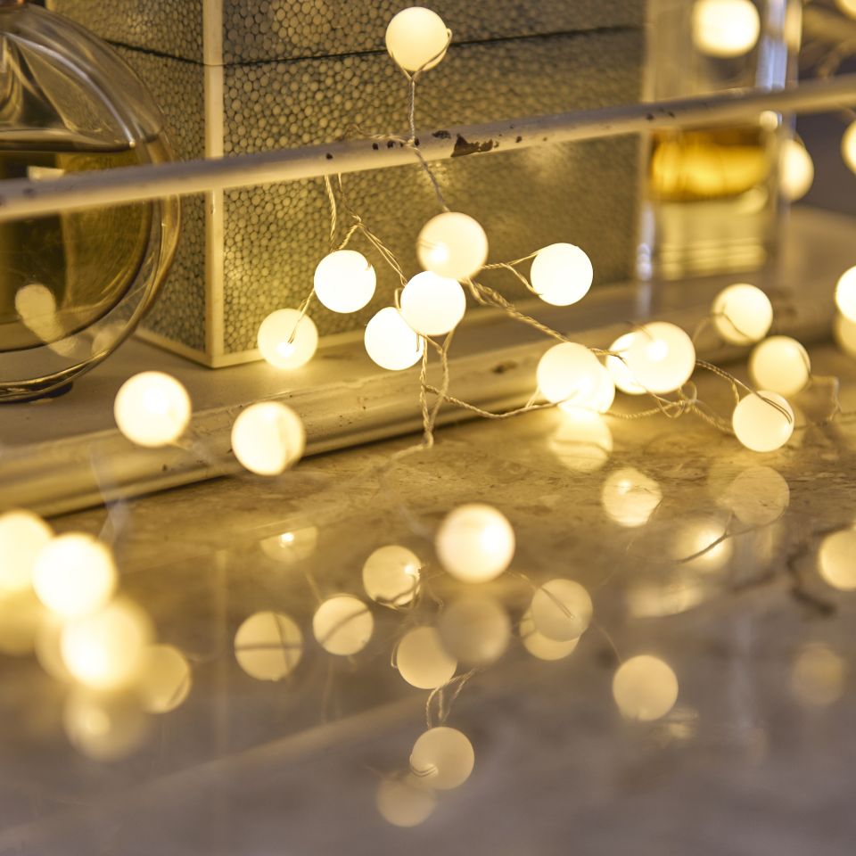 String of white lights on a reflective surface with a blurred background