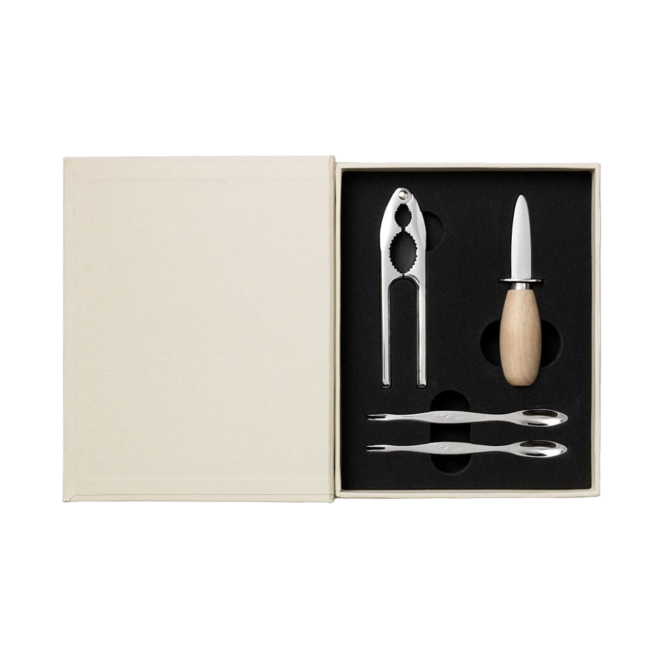 Set of kitchen tools including a cracker, knife, and tongs in a box on a white background