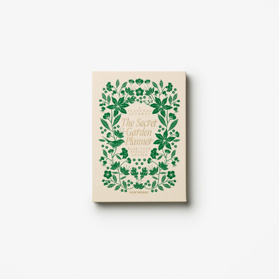 Book titled 'The Sacred Garden Planner' with green floral design on a beige background
