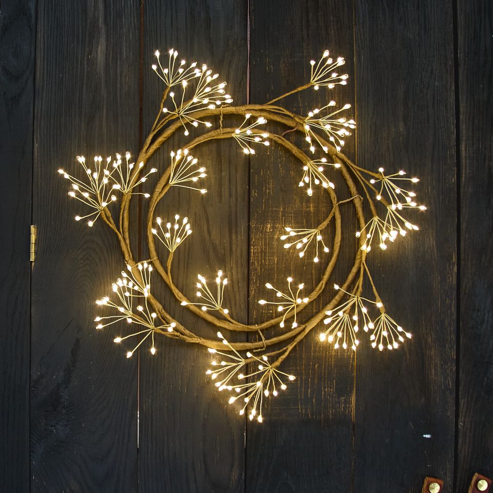 Decorative wreath with string lights on a wooden door