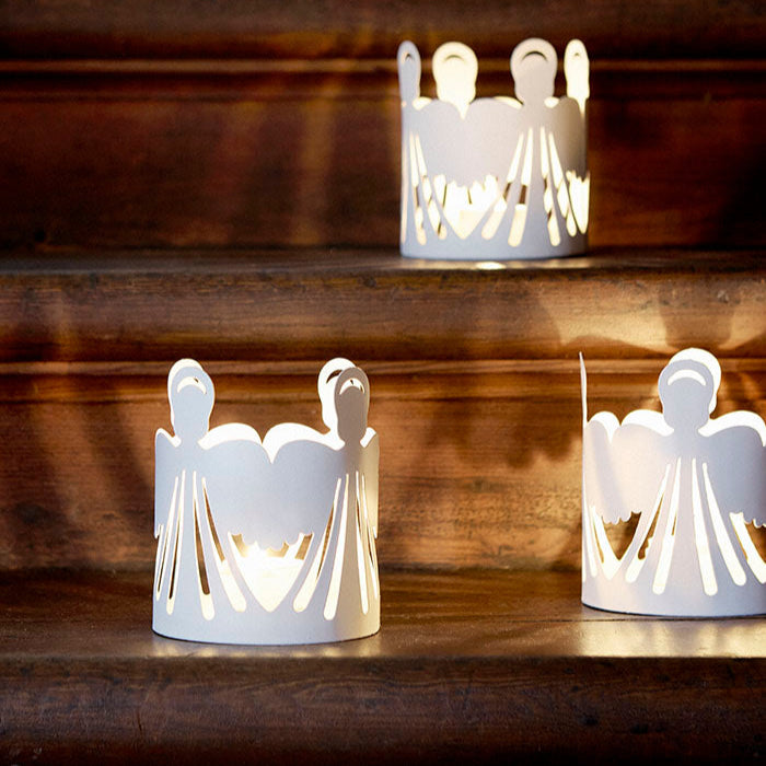 White angel-shaped candle holders on a wooden surface