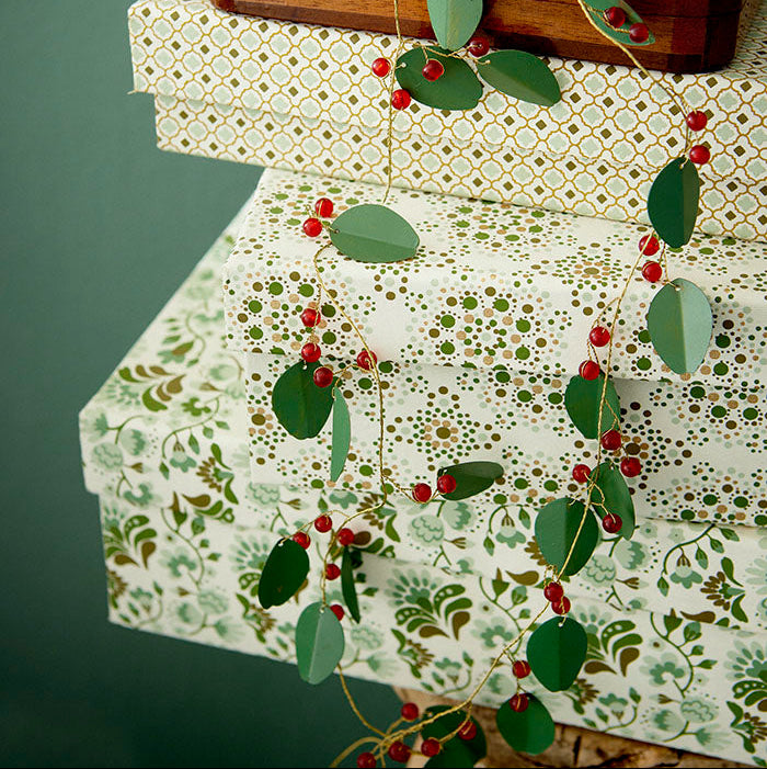Decorative paper with floral pattern and red berries garland draped over.
