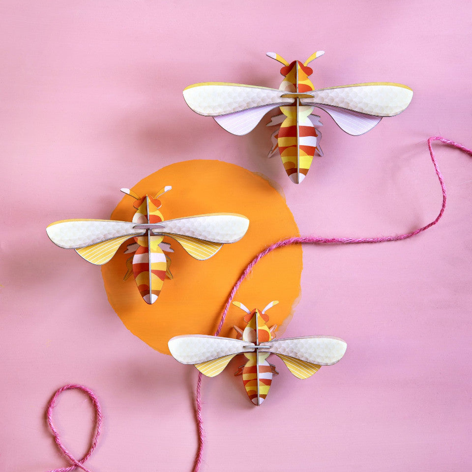 Honey bee wall decoration, set of 3, styled on a pink and orange wall.