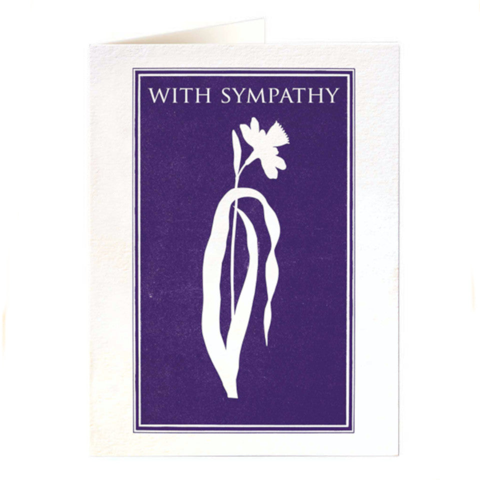 With Sympathy, blank card, white daffodil on indigo background with white lettering, with white envelope.