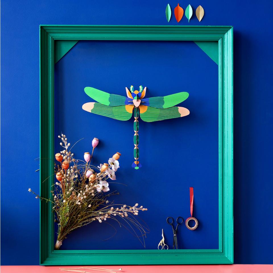 Giant green dragonfly 3D cardboard wall decoration, styled on a blue wall in a green photoframe with dried flowers.