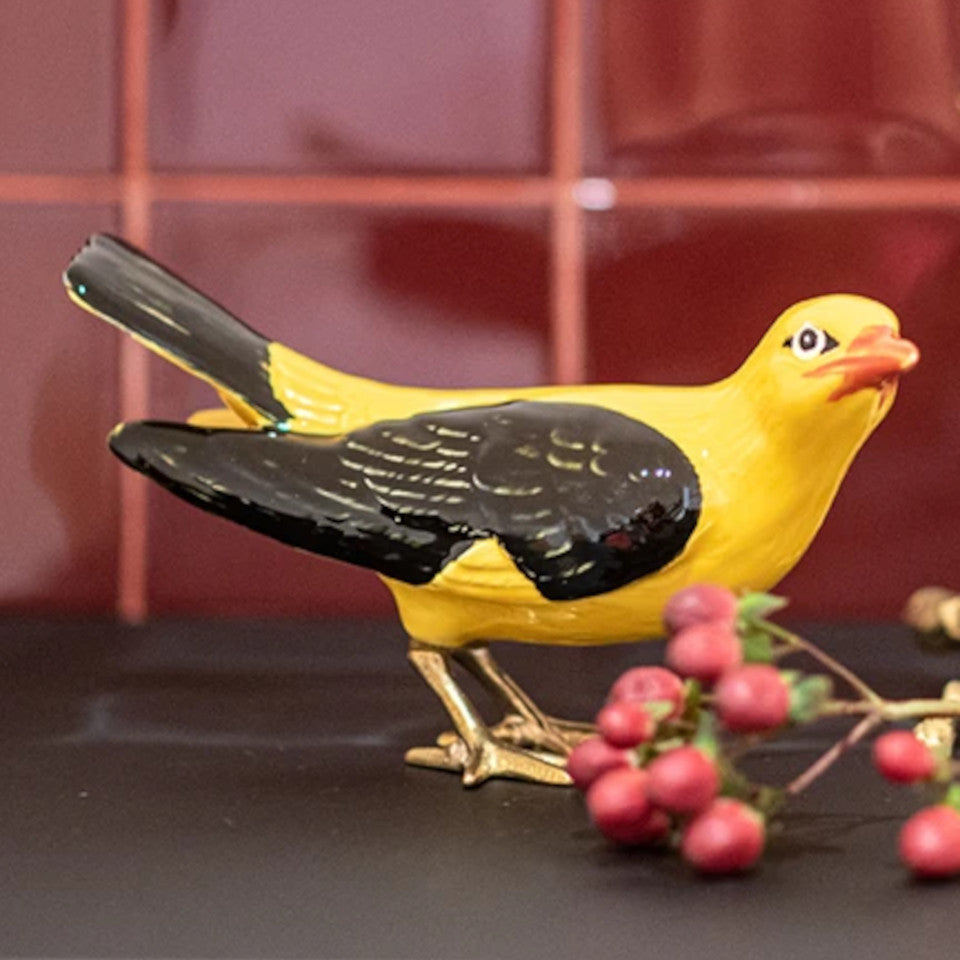 Labatorio D'Estorias Golden Oriole with bright yellow faience head and body, and black fgaience wings and tail, and brass feet styled on a counter with a branch of berries and wine tiled background.
