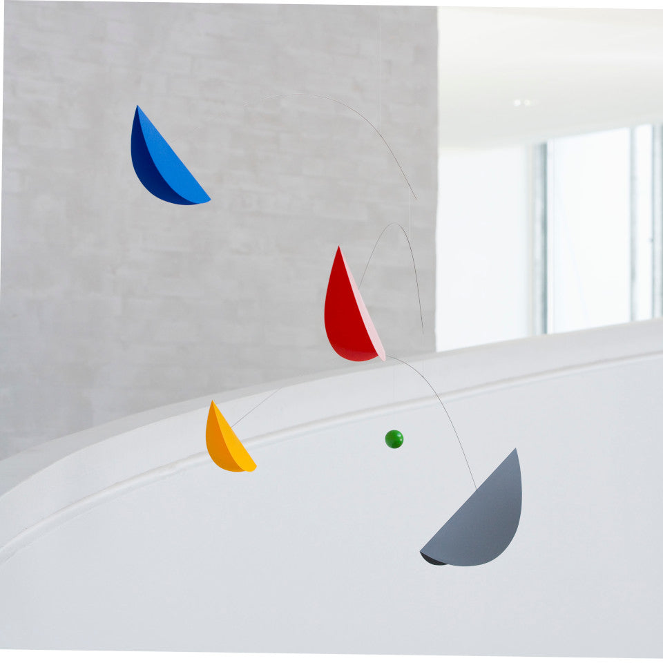 Life and Thread mobile with blue, yellow, grey and red 'sails' orbitting a small green globe, styled in a white room.