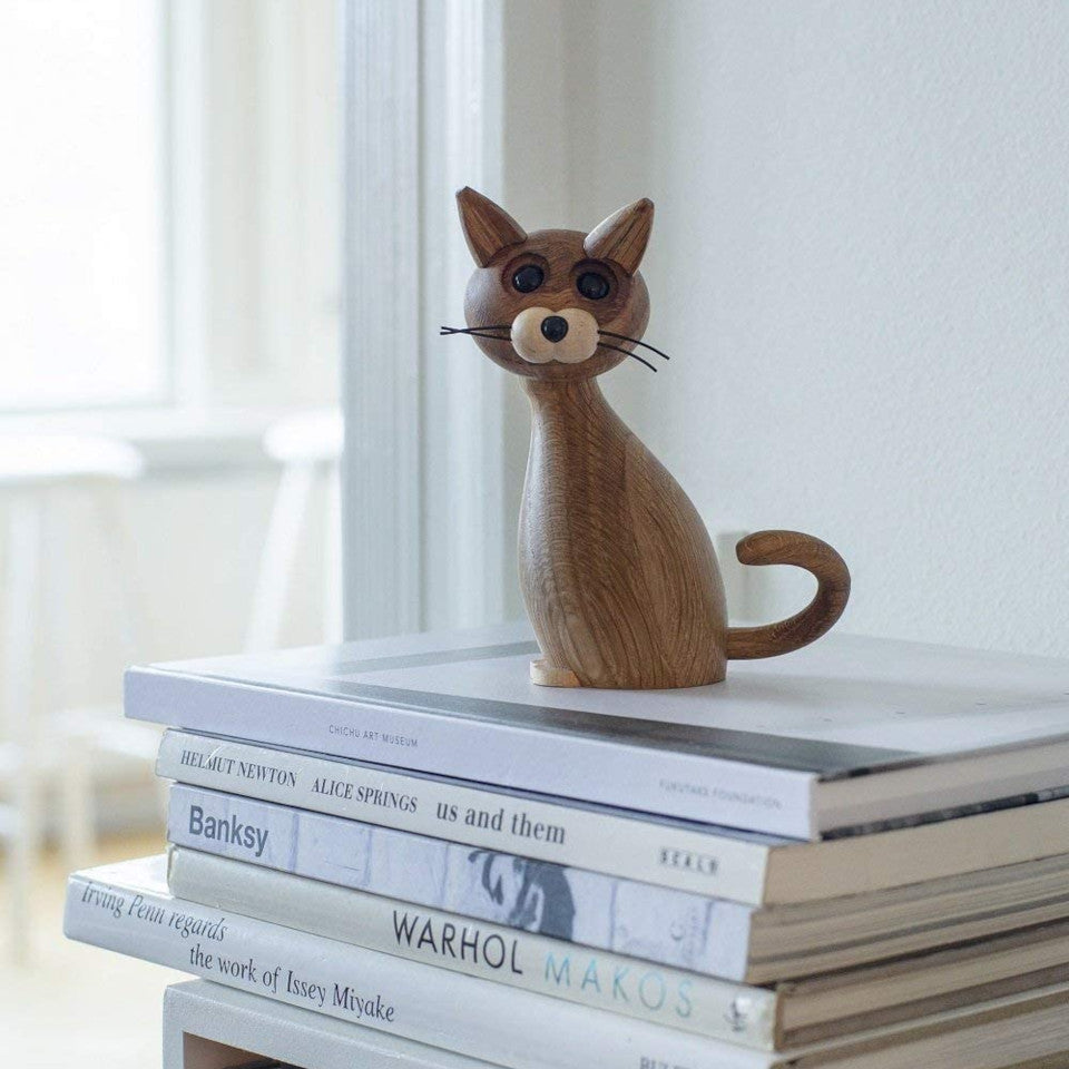 Lucky Cat styled sitting on a pile of books.