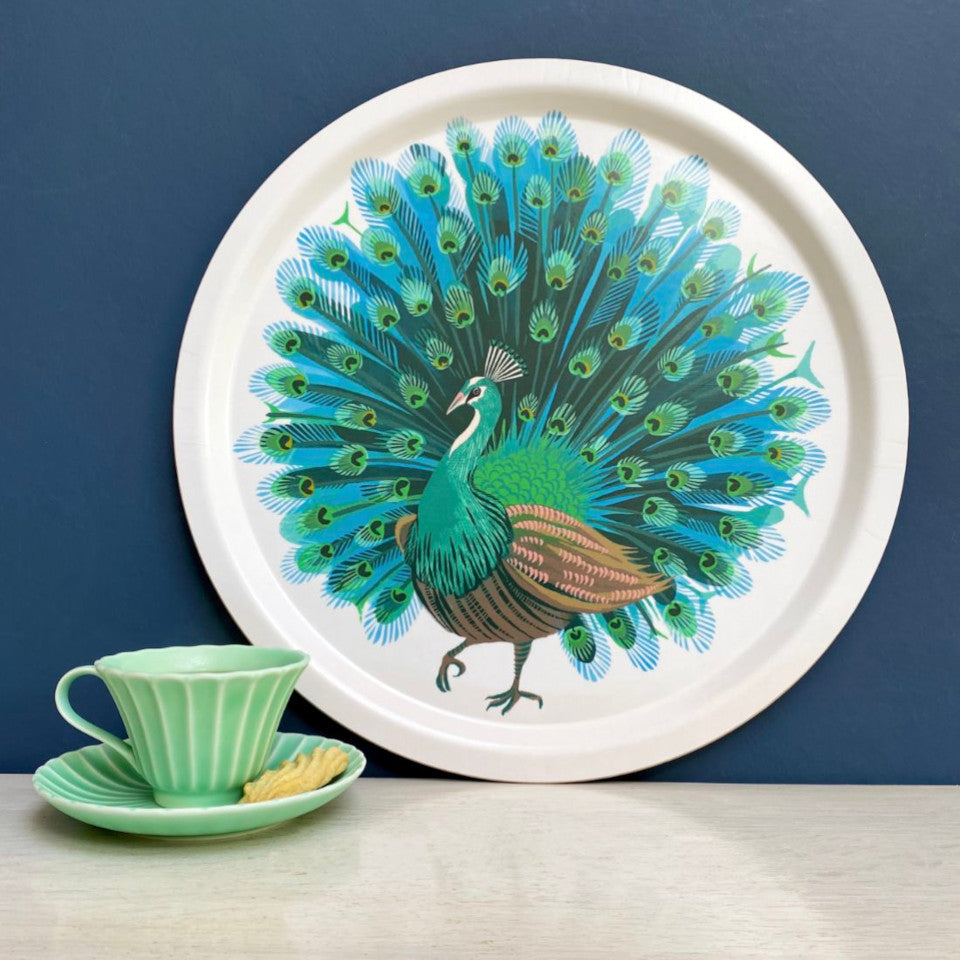 Peacock by Asta Barrington, peacock in full tail-feather on white background, 39cm round tray, styled leaning against a blue painted wall with a mint green vintage teacup and saucer.