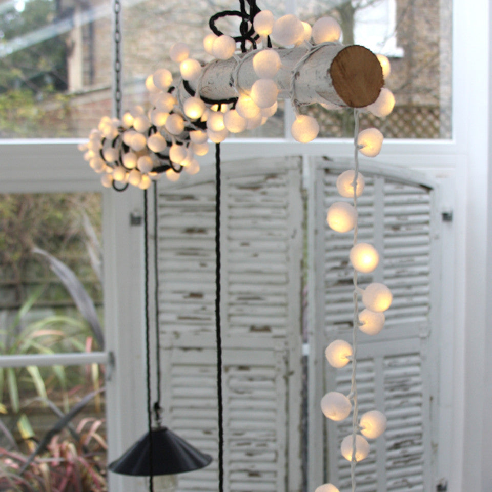 Pom-pom light chain - mains operated, styled wound around a branch with light pendants.