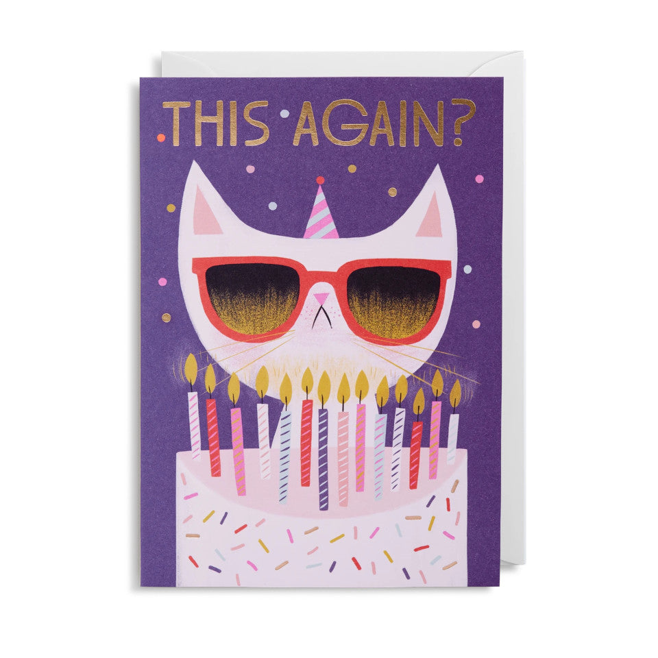 Grumpy Cat This Again?, blank greeting card, with white grumpy cat behind a birthday cake with birthday candles, on a navy background, with white envelope.